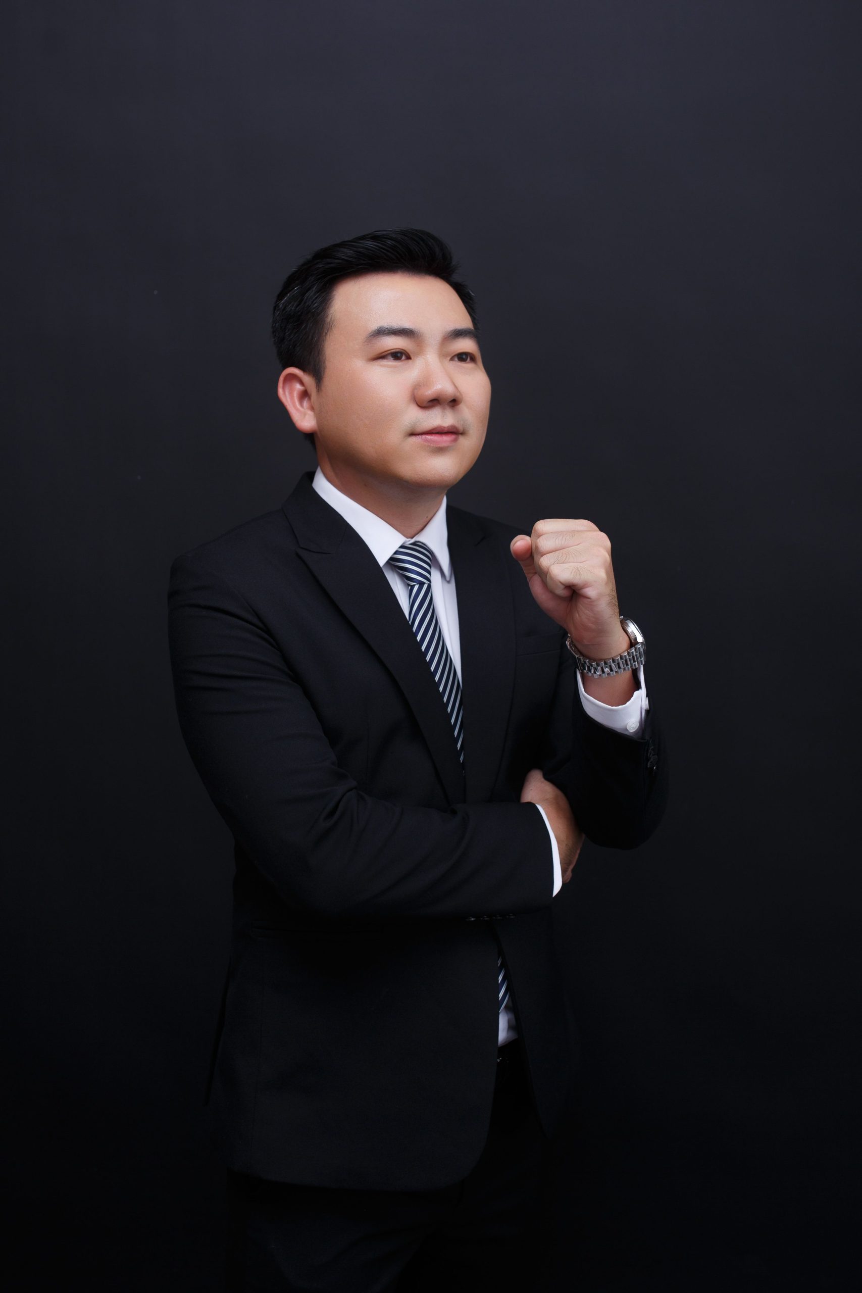 Elegant portrait of a confident businessman wearing a suit against a black background.